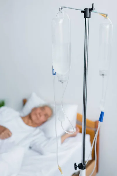 静脉注射治疗站在病床上模糊的病人旁边 — 图库照片