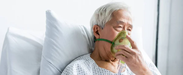 戴氧气面罩的亚洲老年人坐在病床上 高举横幅 — 图库照片