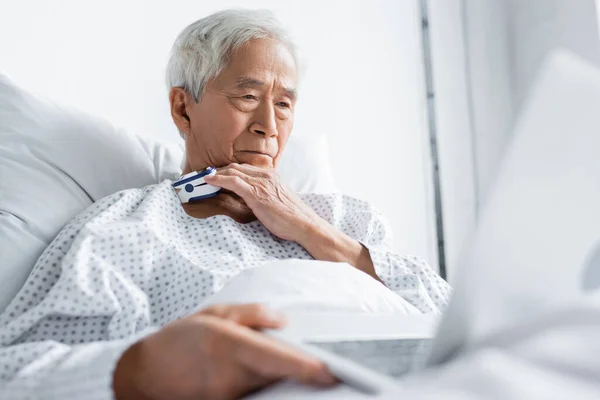 Äldre Asiatiska Patienter Med Pulsoximeter Med Suddig Laptop Sjukhusavdelningen — Stockfoto