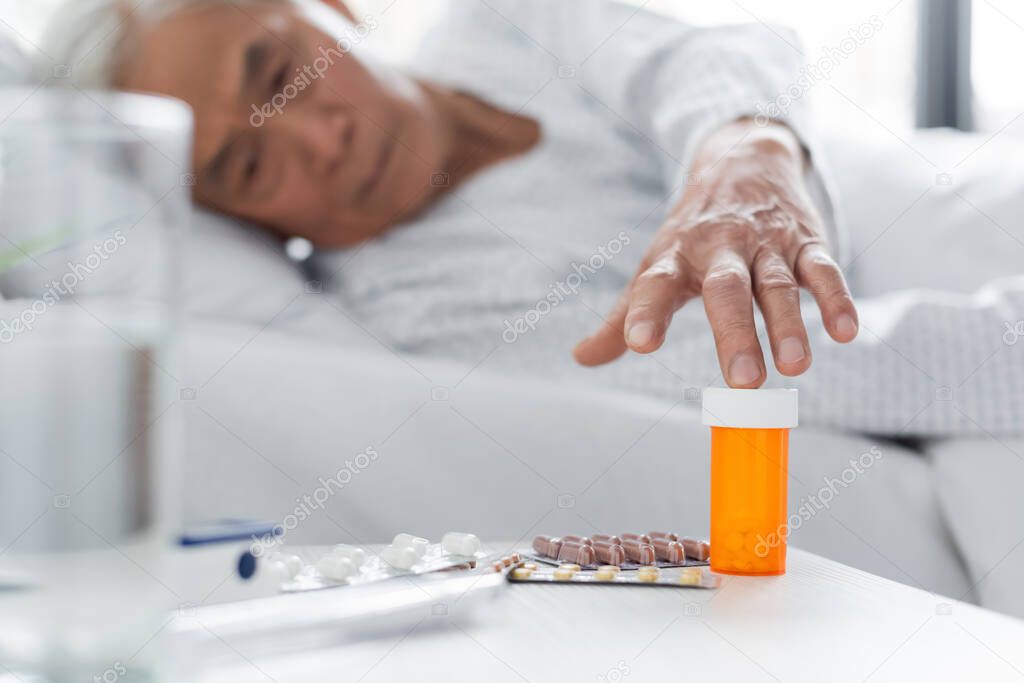 Blurred asian patient taking pills near water in hospital ward 