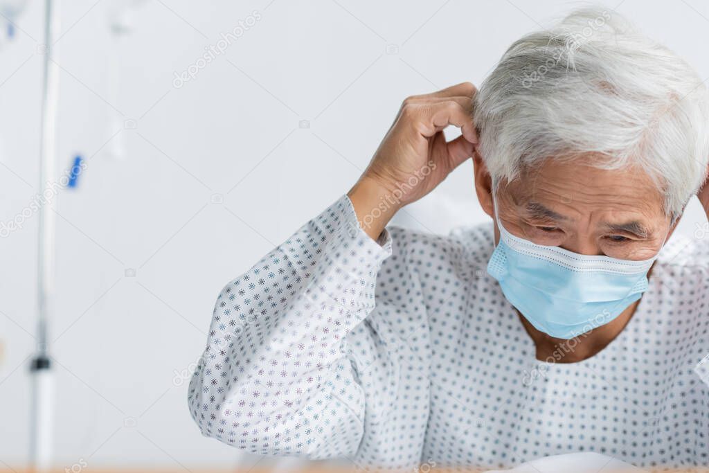 Senior asian patient wearing medical mask in hospital ward 
