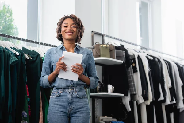 Positive Vendeuse Afro Américaine Tenant Tablette Numérique Près Des Vêtements — Photo