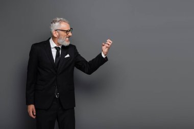Kızgın, orta yaşlı, gözlüklü işadamının gri üzerine izole edilmiş el kol hareketleri.