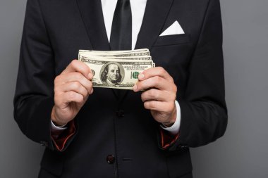 Orta yaşlı bir işadamının, bir dolarlık banknotları gri üzerine sakladığı görüntüler.