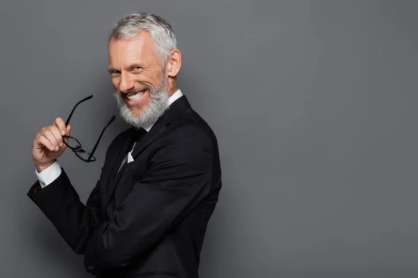 Alegre Hombre Negocios Mediana Edad Sosteniendo Gafas Sonriendo Gris —  Fotos de Stock