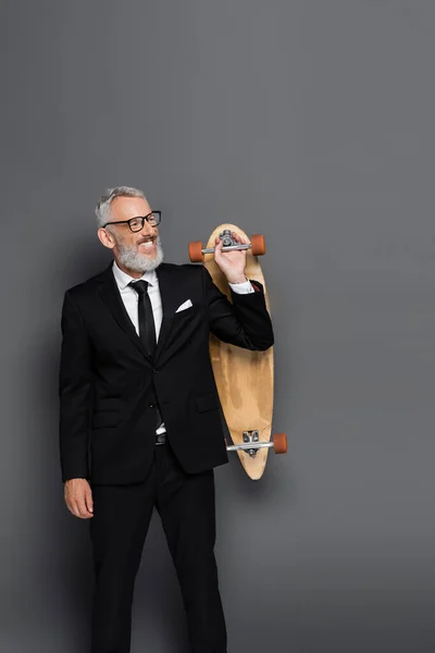 Cheerful Middle Aged Businessman Suit Glasses Holding Longboard Grey — Stock Photo, Image