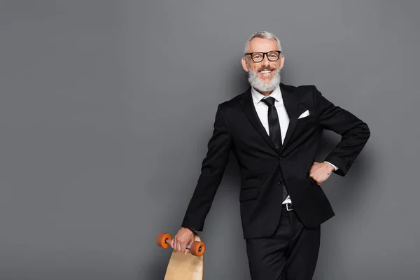 Glad Medelålders Affärsman Kostym Och Glasögon Håller Longboard Samtidigt Poserar — Stockfoto