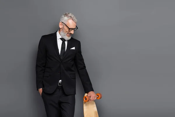 Smiling Middle Aged Businessman Suit Glasses Holding Longboard Grey — Stock Photo, Image