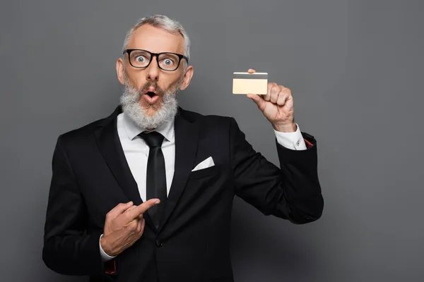Shocked Mature Businessman Suit Glasses Pointing Credit Card Isolated Grey — Stock Photo, Image
