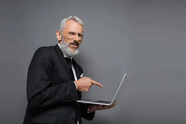 Бізнесмен Середнього Віку Костюмі Вказуючи Пальцем Ноутбук Ізольовано Сірому — стокове фото