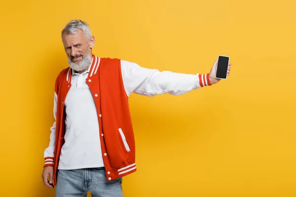 Nespokojený Muž Středního Věku Drží Smartphone Prázdnou Obrazovkou Izolované Žluté — Stock fotografie