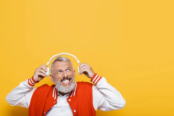 Positive Middle Aged Man Holding Wireless Headphones Isolated Yellow — Stock Photo, Image