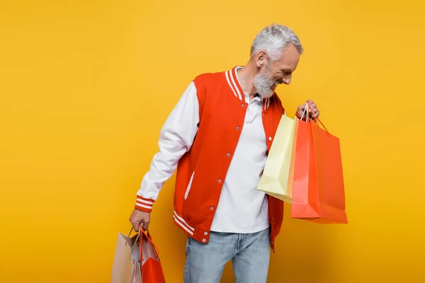 陽気な中年男性で爆撃機ジャケット持ってショッピングバッグ上の黄色 — ストック写真