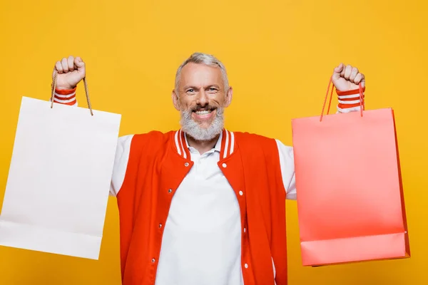 Vreugdevolle Man Van Middelbare Leeftijd Houdt Boodschappentassen Geïsoleerd Geel — Stockfoto