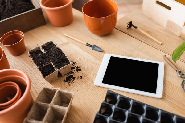 Высокоугольный вид фломастеров рядом с садовыми инструментами и цифровой стол на столе в цветочном магазине 