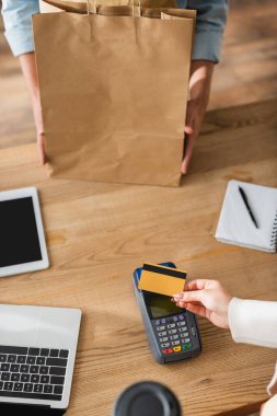 Müşterilerin kredi kartıyla ödeme yapmalarını, çiçekçinin yanında alışveriş çantasıyla ve mağazada aletlerle görüntülemişler. 