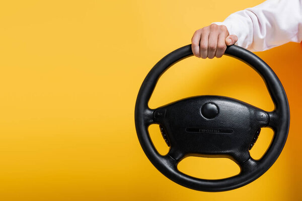 partial view of middle aged man holding steering wheel on yellow