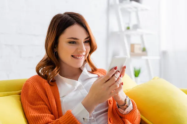 Mujer Emocionada Sentada Sofá Amarillo Mensajería Teléfono Móvil —  Fotos de Stock