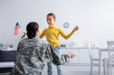 Memleketinde askeri üniformalı bir ailenin yanında Amerikan bayrağı tutan neşeli çocuk. 
