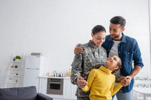 Homem Sorridente Abraçando Esposa Uniforme Militar Segurando Mãos Filha Casa — Fotografia de Stock