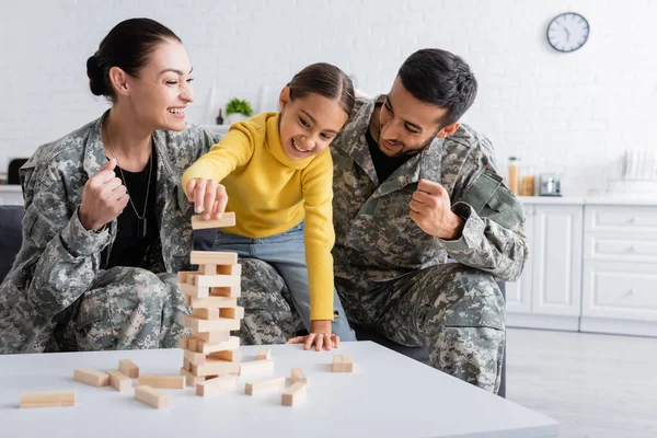 Leende Föräldrar Militäruniform Visar Gest Nära Barn Spelar Trä Block — Stockfoto
