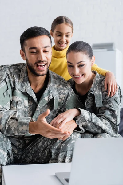 Усміхнені Батьки Військовій Формі Тримають Руки Біля Ноутбука Дочки Вдома — стокове фото