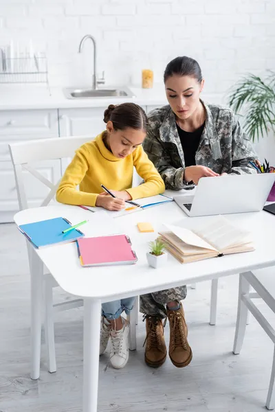 Mother Military Uniform Looking Laptop While Daughter Writing Notebook Home — Stock Photo, Image
