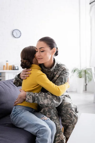 Woman Camouflage Uniform Hugging Daughter Couch Home — Stock Photo, Image