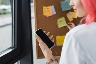 Pembe saçlı, akıllı telefonlu, beyaz ekranlı, yapışkan notlu bir iş kadını görüntüsü. 