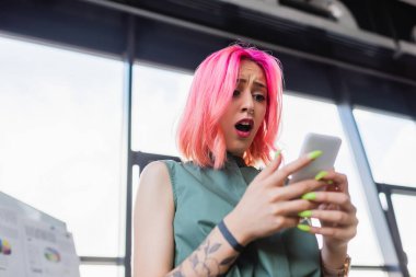 Akıllı telefon kullanan pembe saçlı iş kadınının düşük açılı görüntüsü