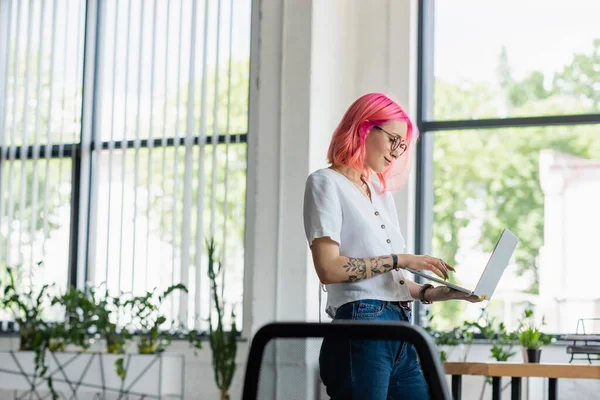 Χαρούμενη Νεαρή Επιχειρηματίας Ροζ Μαλλιά Χρησιμοποιώντας Φορητό Υπολογιστή Στο Γραφείο — Φωτογραφία Αρχείου