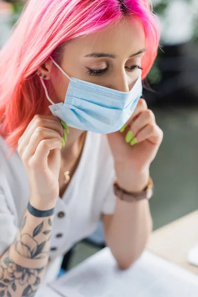 ピンクの髪をした入れ墨のマネージャーオフィスで医療マスクを身に着けている — ストック写真