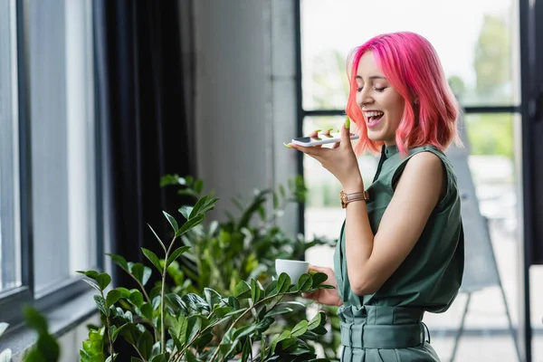 Pozytywny Businesswoman Różowymi Włosami Piercing Trzymając Filiżankę Kawy Podczas Nagrywania — Zdjęcie stockowe