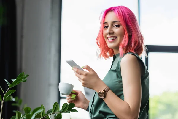 Wesoły Bizneswoman Różowymi Włosami Piercing Trzymając Filiżankę Kawy Smartfona — Zdjęcie stockowe