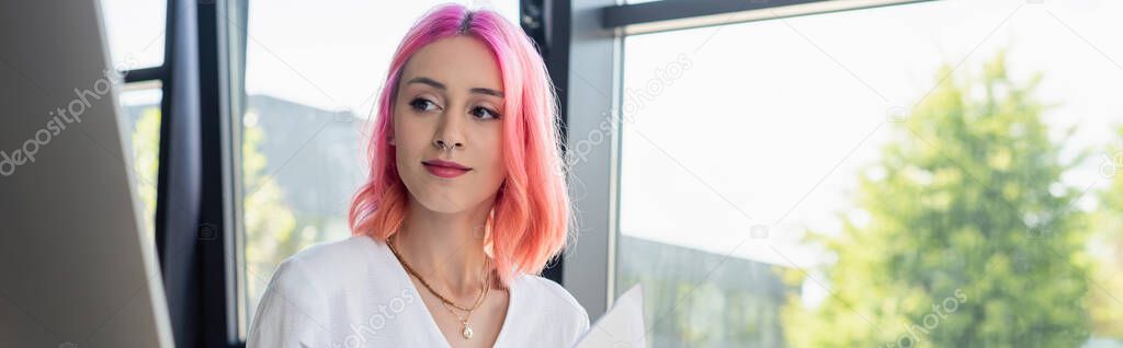 pierced businesswoman with pink hair looking at computer monitor, banner