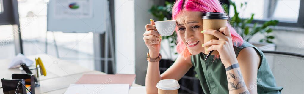 worried businesswoman with pink hair holding coffee in office, banner