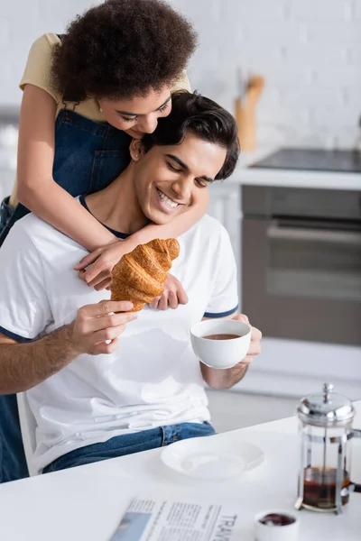 Happy African American Woman Hugging Boyfriend Cup Tea Croissant Kitchen — Stock Photo, Image