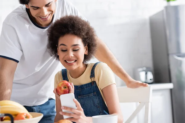 Vrolijk Interraciaal Paar Zoek Naar Smartphone Tijdens Het Ontbijt — Stockfoto