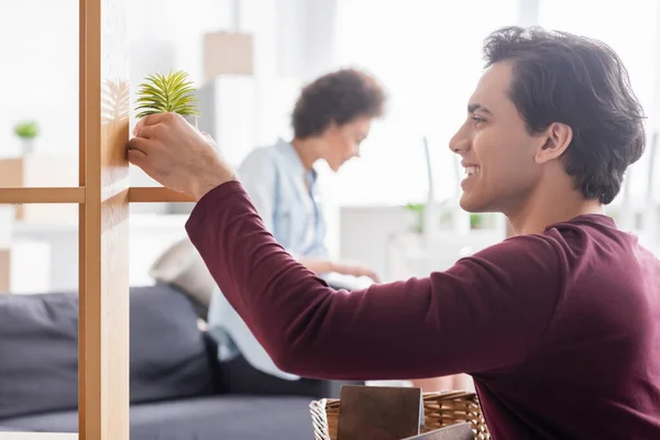 Vista Lateral Del Hombre Feliz Sosteniendo Cesta Planta Cerca Rack — Foto de Stock