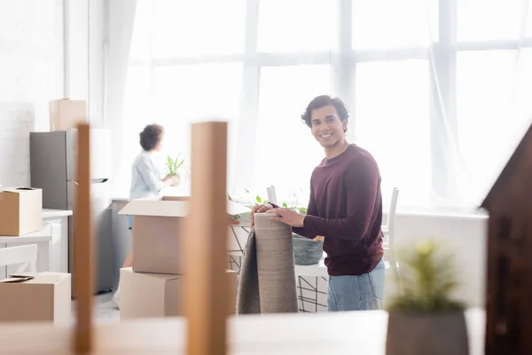 Happy Man Holding Rolled Carpet Blurred Girlfriend — Stock Photo, Image