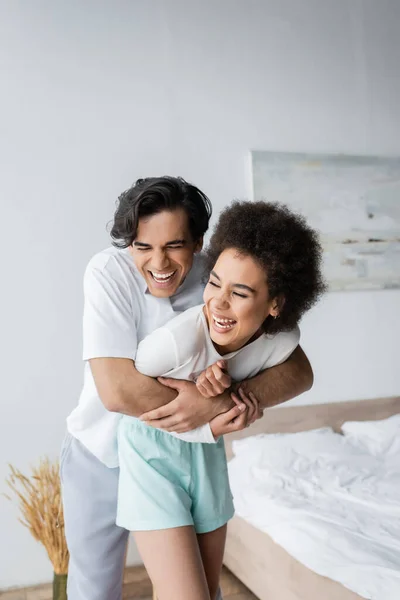 Happy Multiethnic Couple Laughing Hugging Bedroom — Stock Photo, Image