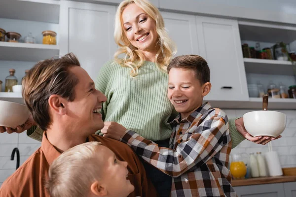 Happy Woman Holding Bowls Breakfast Husband Sons Kitchen — Stock Photo, Image