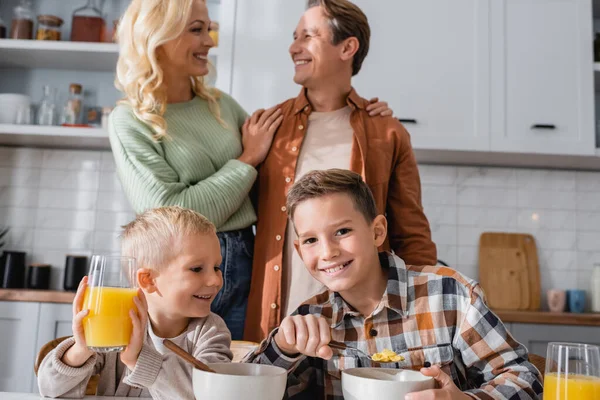 Vreugdevolle Broers Ontbijten Buurt Van Ouders Knuffelen Wazig Achtergrond — Stockfoto