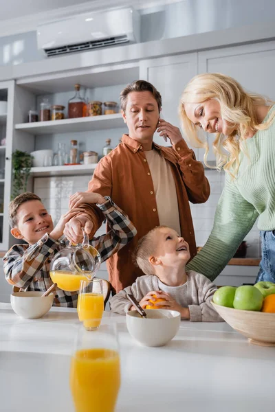 Man Hälla Apelsinjuice När Pratar Smartphone Frukost Med Familjen — Stockfoto