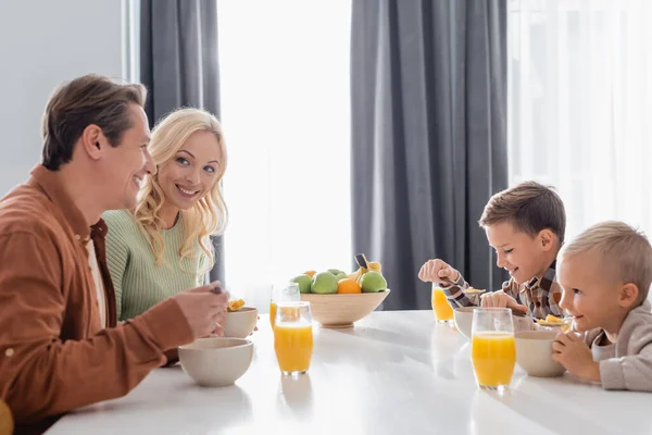 Vrolijk Ouders Met Zonen Eten Cornflakes Buurt Van Sinaasappelsap Vers — Stockfoto