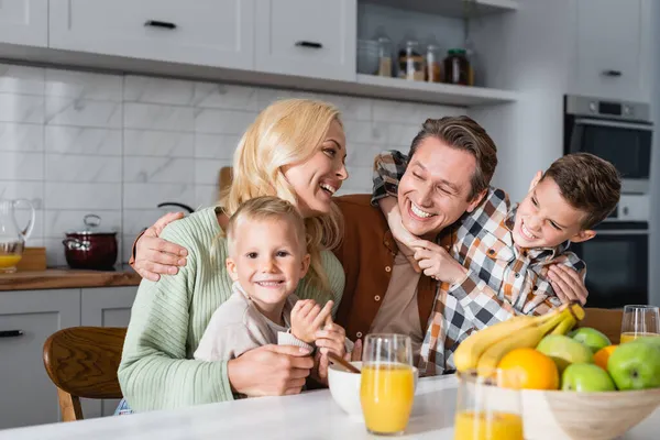 Задоволені Батьки Сини Обіймаються Під Час Сніданку Біля Апельсинового Соку — стокове фото