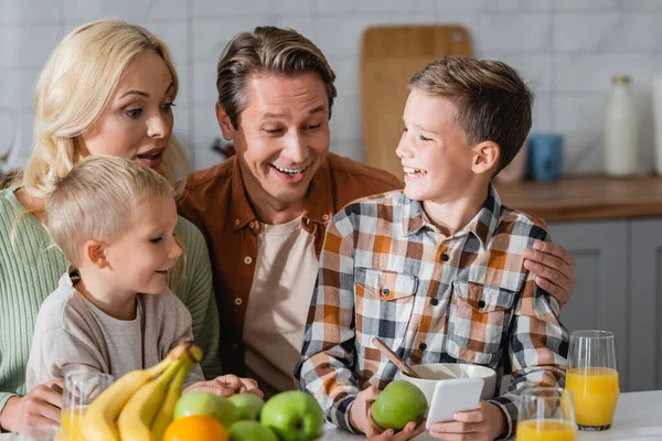 Niño Sosteniendo Teléfono Inteligente Durante Desayuno Con Hermano Los Padres — Foto de Stock