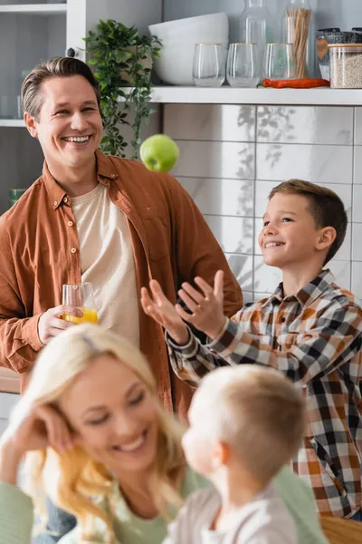 Menino Feliz Malabarismo Com Maçã Durante Café Manhã Com Família — Fotografia de Stock