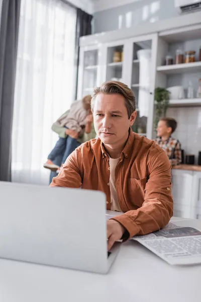 Homem Digitando Laptop Borrado Perto Jornal Família Cozinha — Fotografia de Stock