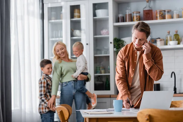 Hombre Escribiendo Cuaderno Hablando Teléfono Inteligente Mientras Trabajaba Cocina Cerca — Foto de Stock